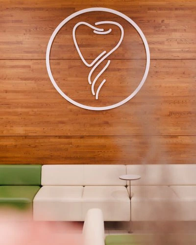 Sala de espera del Centro Odontológico Miguel González, clínica dental en Oviedo, con el logotipo del centro en la pared de madera