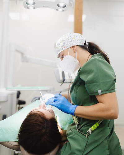 Odontóloga realizando un tratamiento periodontal a una paciente en el Centro Odontológico Miguel González, clínica dental en Oviedo